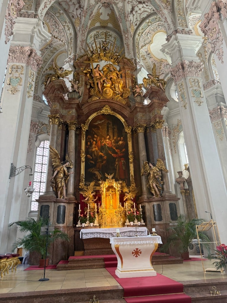 Inside the Heilig-Geist-Kirche (Church of the Holy Spirit) near Viktualienmarkt in Munich, with Rococo stucco and a gilded high altar flanked by adoring angels